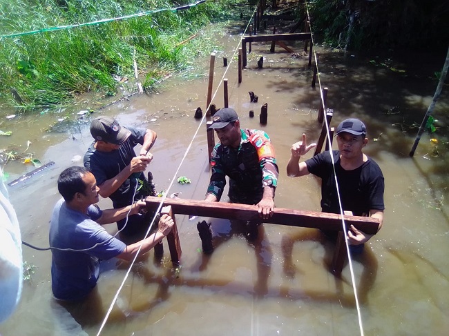 Anggota Koramil Bantu Masyarakat Desa Biwan Membangun Jembatan