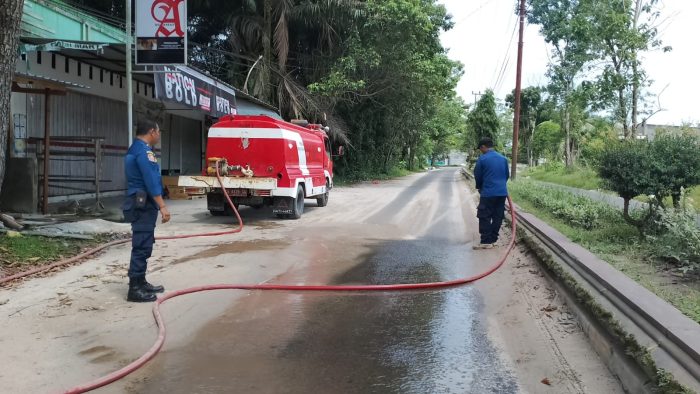 Gerak Cepat, Damkar Kobar Siram Jalan Berpasir yang Rawan Laka Lantas